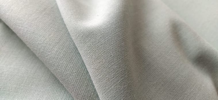 white fabric with interlacing threads close-up. Light green tint. Nice beautiful waves on the material. A neatly folded piece of fabric. Interior decoration, tailoring. Textile industry.
