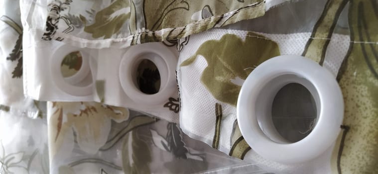 Plastic rings for attaching the fabric to the curtain rod. White plastic organza tulle eyelets. Light curtain in beige, brown or orange colors. White non-woven fabric. Finished textile edge. Interior element