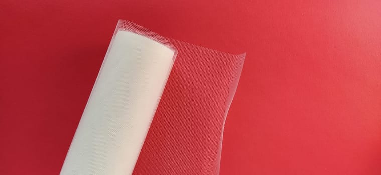 Fabric - white mesh in a roll on a red background. Nylon tape for tying bows on hair. A skein of tulle fabric. Copy space.
