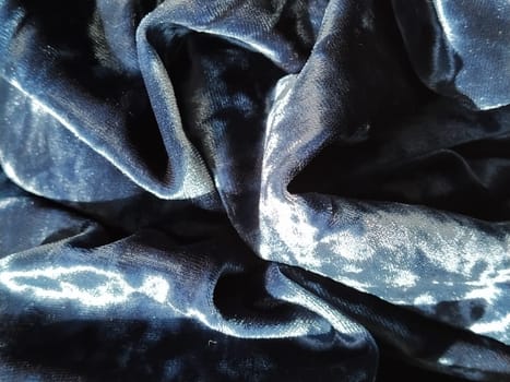 Velvet velor cloth background with glowing light and dark shadows. Background for theater and fashion design themes. Nice blue fabric with overflow.