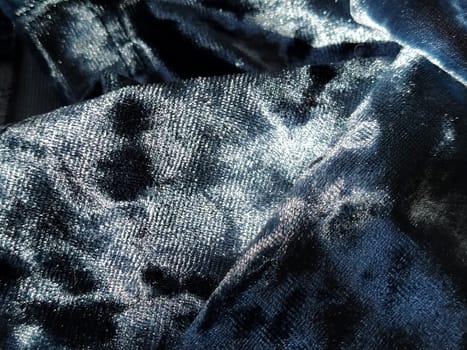 Velvet velor cloth background with glowing light and dark shadows. Background for theater and fashion design themes. Nice blue fabric with overflow.
