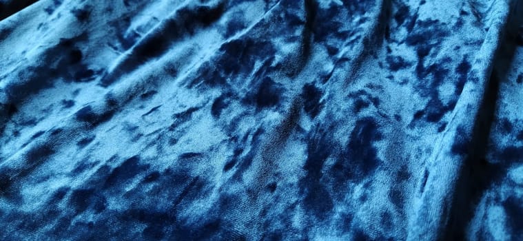 Velvet velor cloth background with glowing light and dark shadows. Background for theater and fashion design themes. Nice blue fabric with overflow.