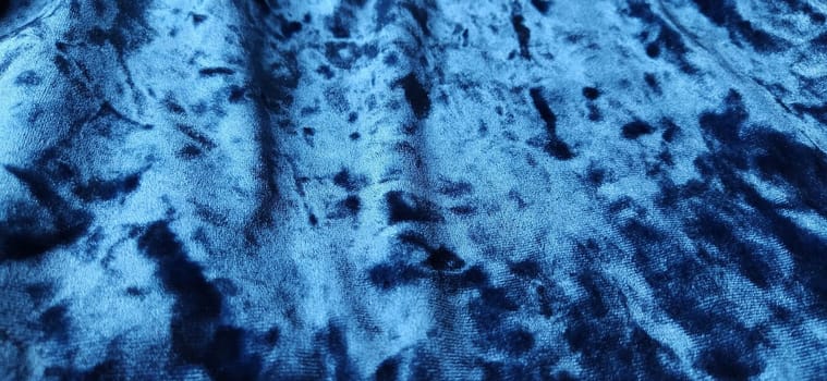 Velvet velor cloth background with glowing light and dark shadows. Background for theater and fashion design themes. Nice blue fabric with overflow.
