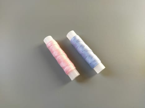 Spools of pink and blue thread on a gray background. Textile industry.