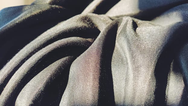 black fabric with interlacing threads close-up. Dark blue tint. Nice beautiful waves on the material. A neatly folded fabric. Interior decoration, sewing clothes and curtains. Textile industry.