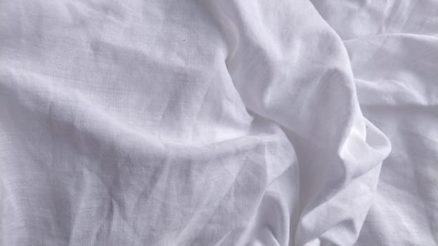 White cotton fabric, not ironed and crumpled in waves. White background. Tablecloth or sheet