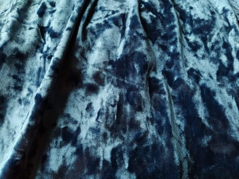 Velvet velor cloth background with glowing light and dark shadows. Background for theater and fashion design themes. Nice blue fabric with overflow.