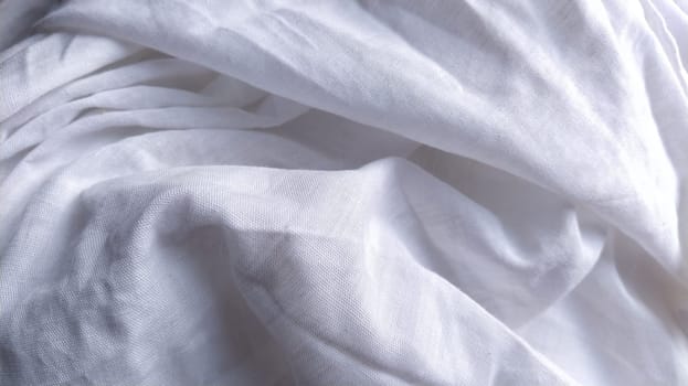 White cotton fabric, not ironed and crumpled in waves. White background. Tablecloth or sheet