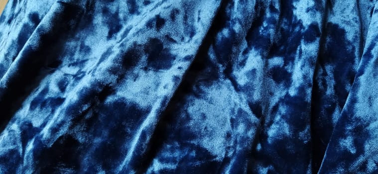 Velvet velor cloth background with glowing light and dark shadows. Background for theater and fashion design themes. Nice blue fabric with overflow.