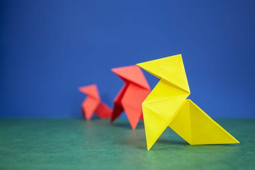 Paper hen origami over green and blue paper background
