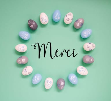 Flat Lay With French Text Merci Means Thank You. Easter Egg Arrangement, Decoration And Ornament. Light Green Paper Background