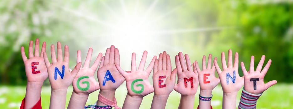Children Hands Building Colorful German Word Engagement Means Commitment. Sunny Green Grass Meadow As Background.