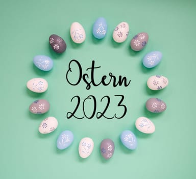 Flat Lay With German Text Ostern 2023 Means Easter 2023. Easter Egg Arrangement, Decoration And Ornament. Light Green Paper Background
