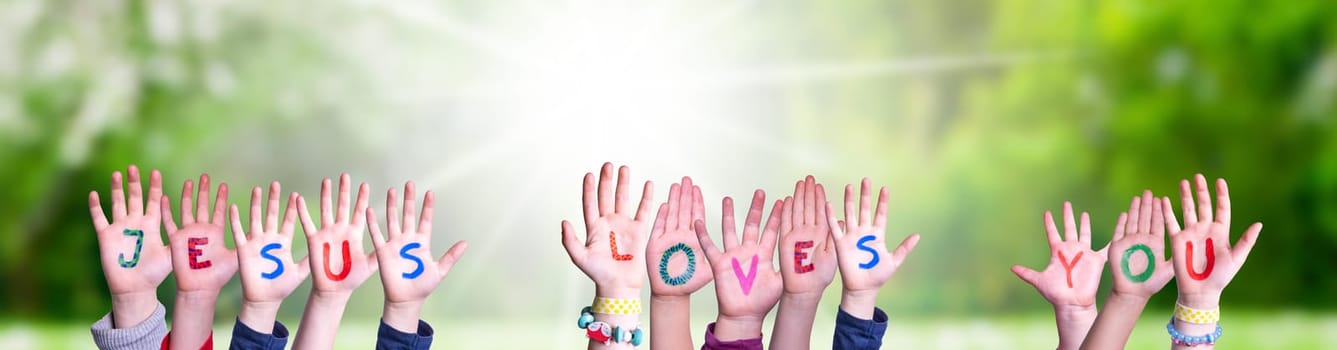 Children Hands Building Colorful English Word Jesus Loves You. Sunny Green Grass Meadow As Background.