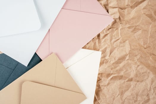 Background image of rough crumpled recycled textured kraft paper with multi-colored cardboard envelopes. Top view. Copy space