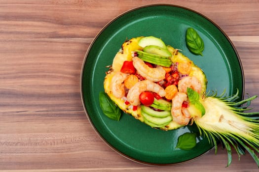 Salad in pineapple with rice, vegetables and shrimps on the table