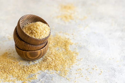 Wooden bowls with Dry uncooked bulgur wheat grain close up, copy space. Vegetarian and Vegan, Mediterranean and Middle Eastern cuisine. Healthy lifestyle