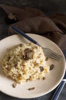 Risotto with wild porcini mushrooms and black truffles from Italy served in a plate close up on grey table, copy space. Eating Italian gourmet cousine