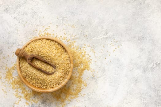 Raw Dry bulgur wheat grain in a wooden bowl with a scoop top view copy space. Vegetarian and Vegan, Mediterranean and Middle Eastern cuisine. Healthy lifestyle
