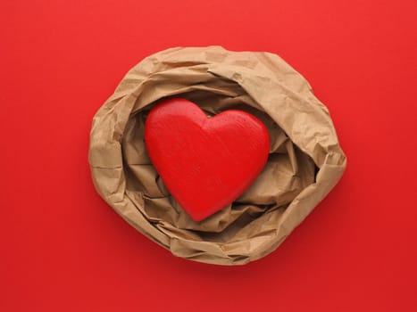 Wooden Heart decoration on crumpled beige paper and red paper background with space for text