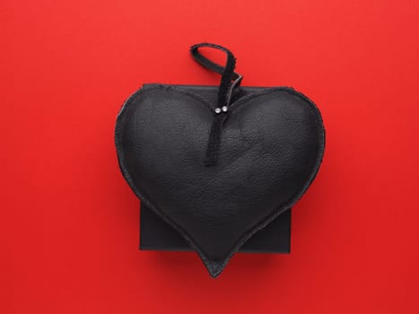 Black leather heart on a black gift box on red background, Valentines or Birthday, lovebackground