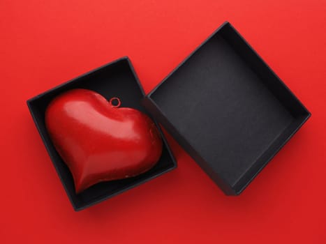 Red metal heart in a black gift box on red background, Valentines or Birthday concept