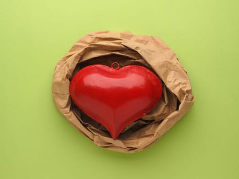 Red metal heart decoration on crumpled beige paper and red paper background with space for text