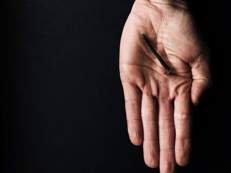 Hand with an old rusty nail symbolizes the crucifixion of Jesus. Easter concept with text free space