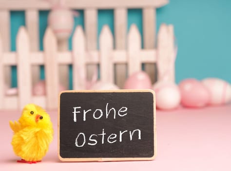 Close up of a cute chick with the German words Happy Easter and an Easter egg background