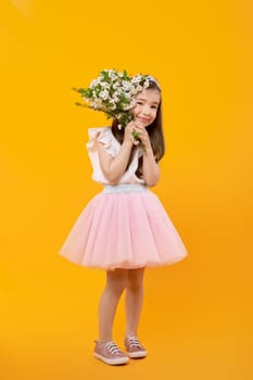 Full body portrait of cute little girl with spring flowers in hands