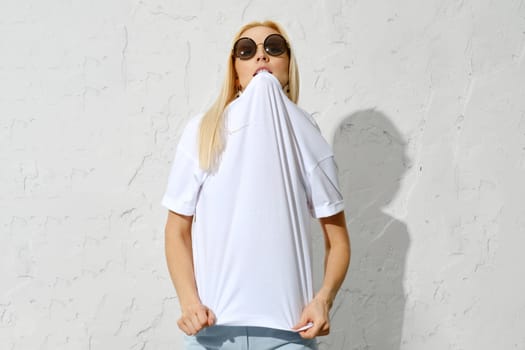 Playful blonde woman bites the collar of a t-shirt