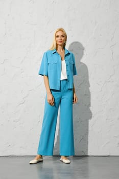 Fashion model in blue jacket and trousers posing under harsh light