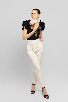Classy adult woman holds flower in hand and looking to the side