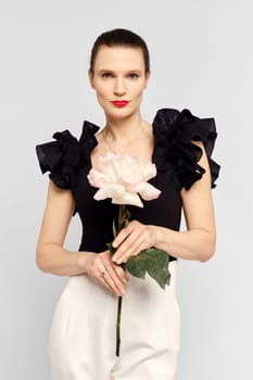 Gorgeous woman with healthy skin and natural makeup holds big rose in hand