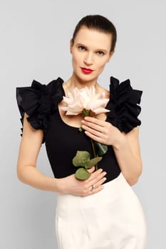 Studio festive portrait of charming adult woman with flower in hands