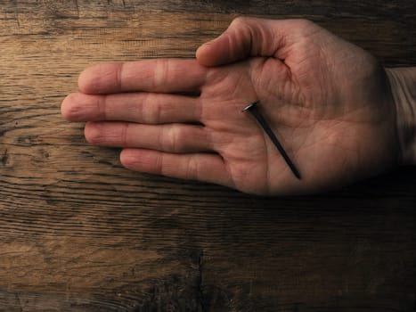 Hand with an old rusty nail symbolizes the crucifixion of Jesus. Easter concept with text free space