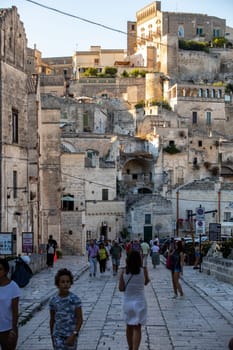 Matera, Italy - September 14, 2019: Tourists during a walk on Cobblestone street in the Sassi di Matera a historic district in the city of Matera. Basilicata. Italy