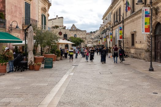 Matera, Italy - September 20, 2019: Tourists during a walk on Cobblestone street in the Sassi di Matera a historic district in the city of Matera. Basilicata. Italy