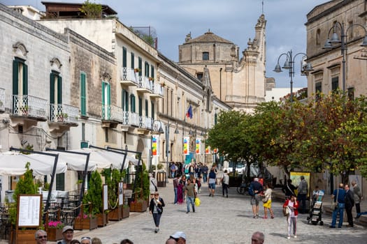 Matera, Italy - September 15, 2019: Tourists during a walk on Cobblestone street in the Sassi di Matera a historic district in the city of Matera. Basilicata. Italy