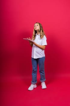 Online school app. Schoolgirl showing tablet computer Empty Screen On red Background. Studio Shot