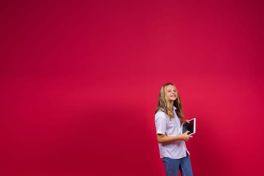 Online school app. Schoolgirl showing tablet computer Empty Screen On red Background. Studio Shot