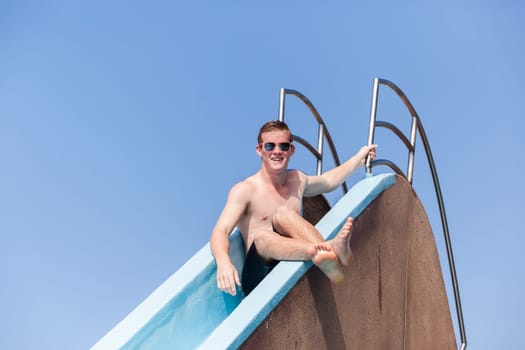 Boy teenager on pool slide summer fun.