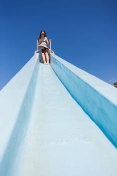 Girl teenager on swimming pool water slide summer fun.