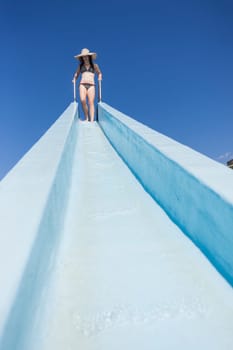 Girl teenager on swimming pool water slide summer fun.