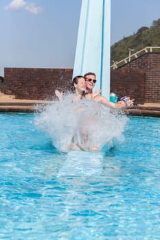 Girl boy teen on swimming  pool slide summer fun.