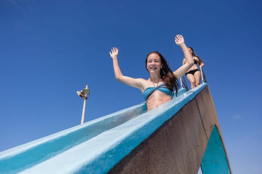 Girl teen on swimming pool water slide summer fun.