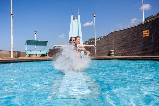 Girl boy teen on swimming  pool slide summer fun.
