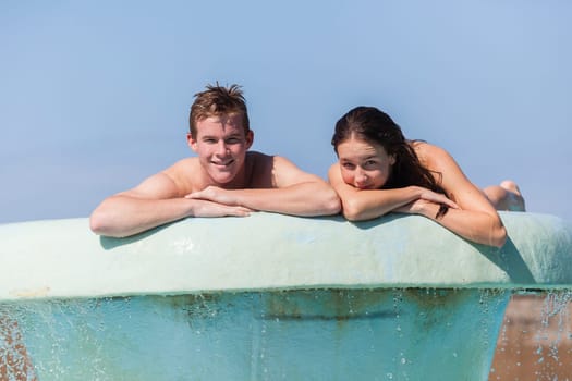 Girl Boy teenagers at beach pool summer holidays talk laughter swimming happy fun.