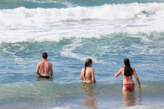Boy Girls teenagers at beach swimming sea ocean shorebreak waves fun