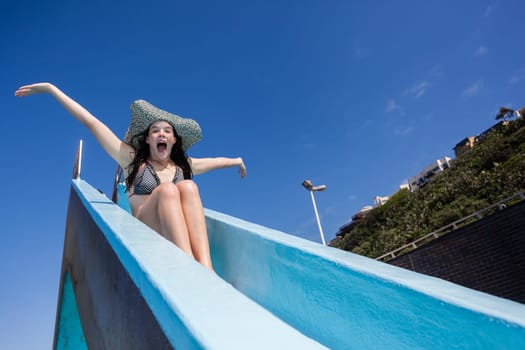 Girl teenager on swimming pool water slide summer fun.